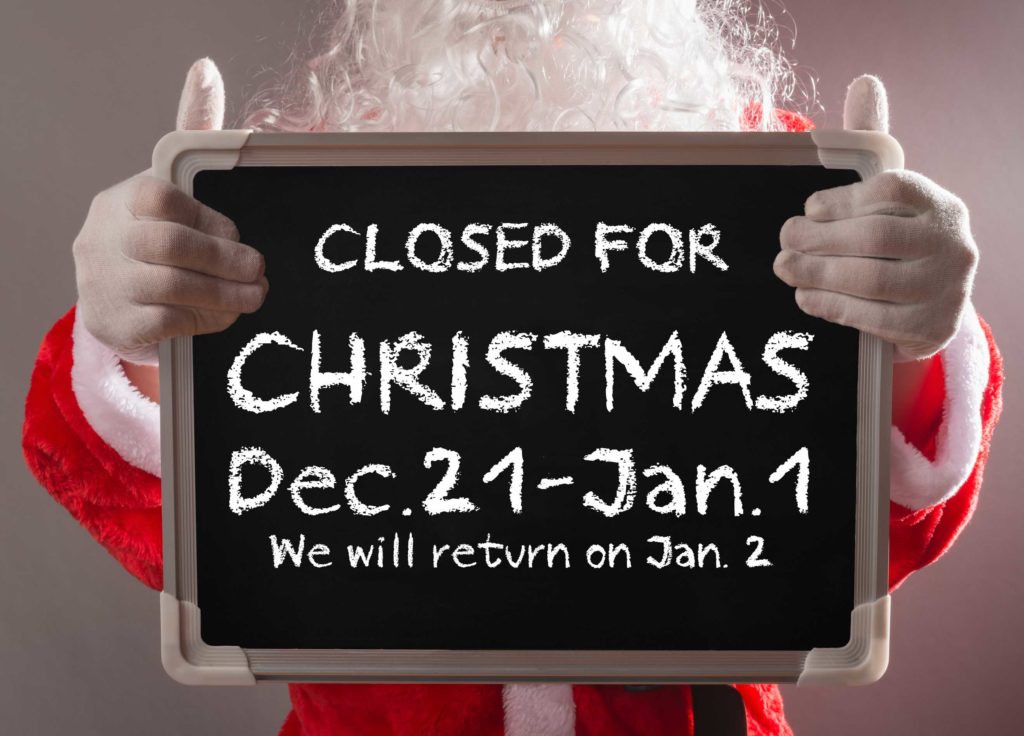 Santa holding a chalkboard informing patients Michael Gillespie Family Dentistry is closed December 21-January 1